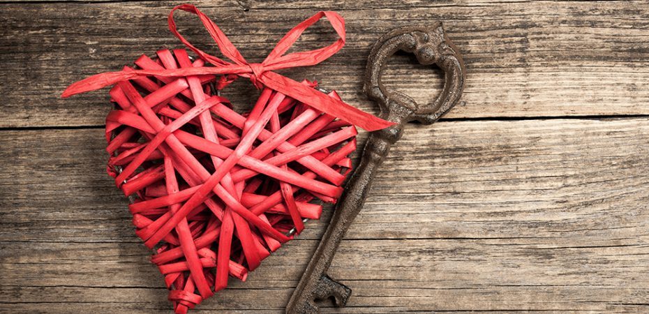 Red wicker heart and vintage key on wooden background